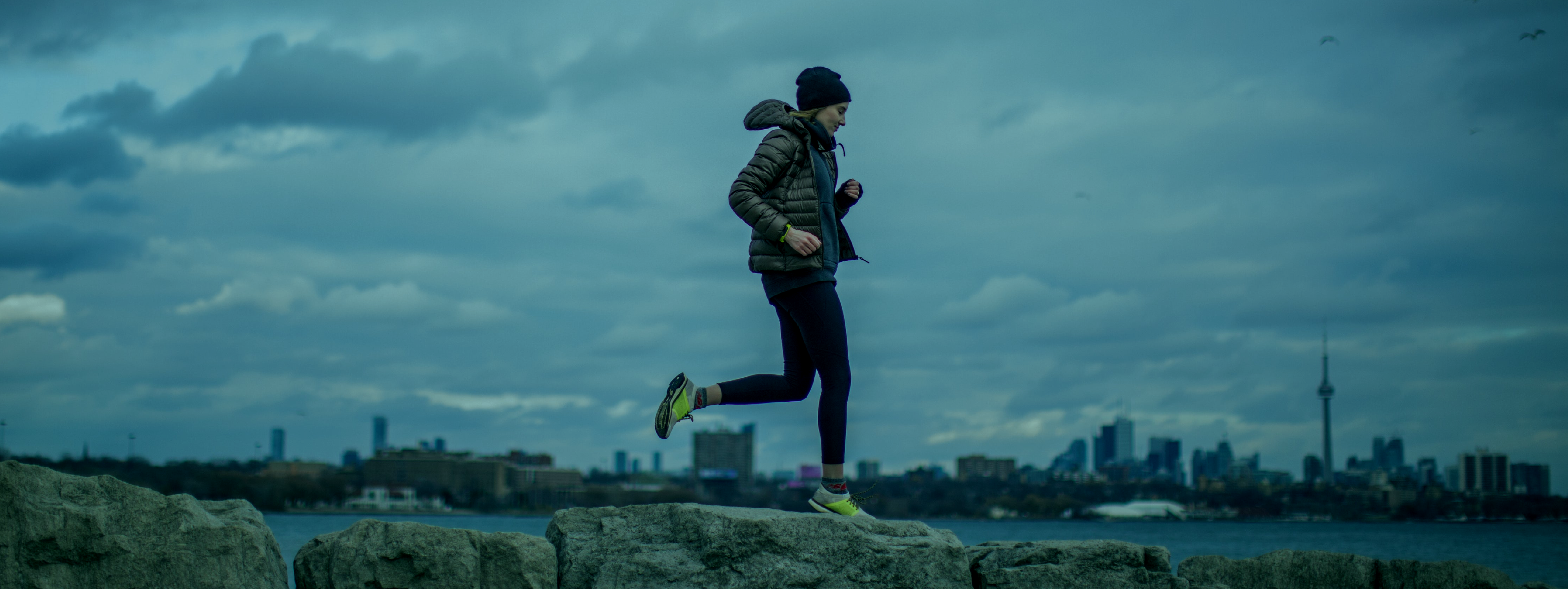 Woman jogging with city in the background.